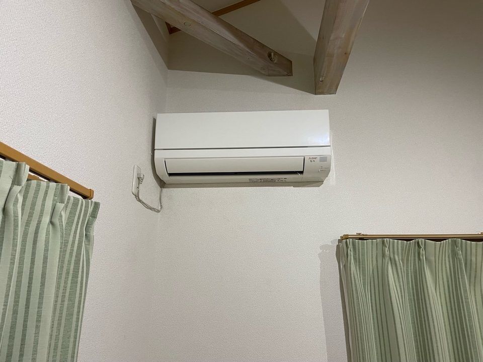 白い壁に設置されたエアコン室内機とコンセントまわり